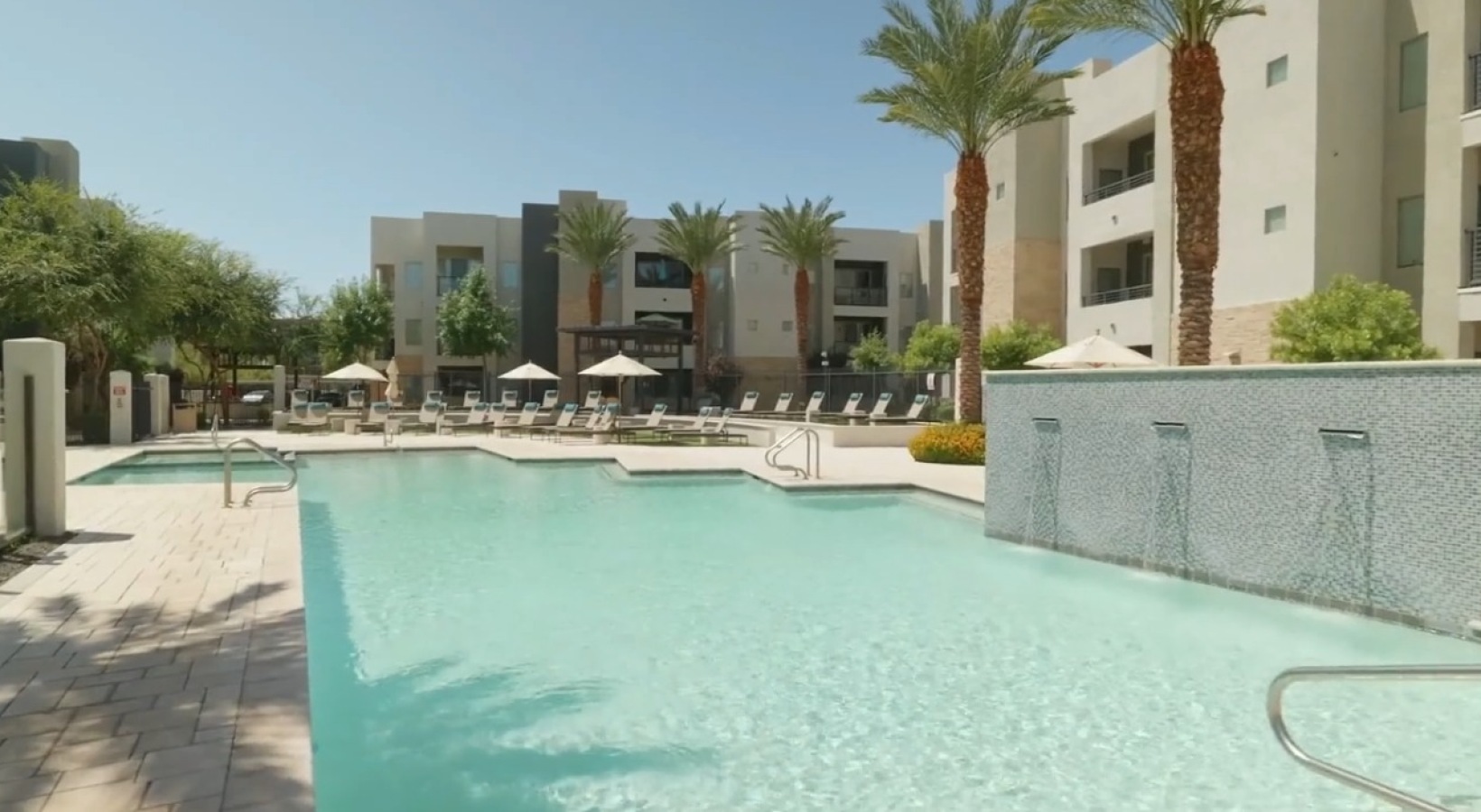 Relax and unwind poolside a pool by a building with palm trees